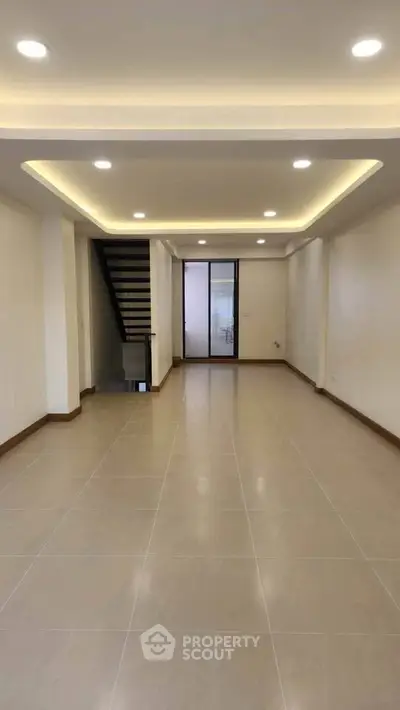 Spacious modern living room with recessed lighting and staircase