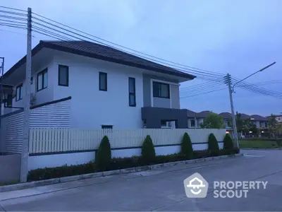 Modern two-story house with sleek design and spacious driveway in serene neighborhood.