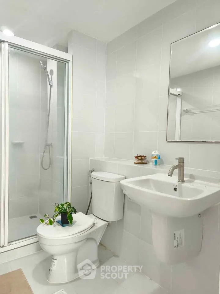 Modern bathroom with shower cabin, white fixtures, and a sleek design.