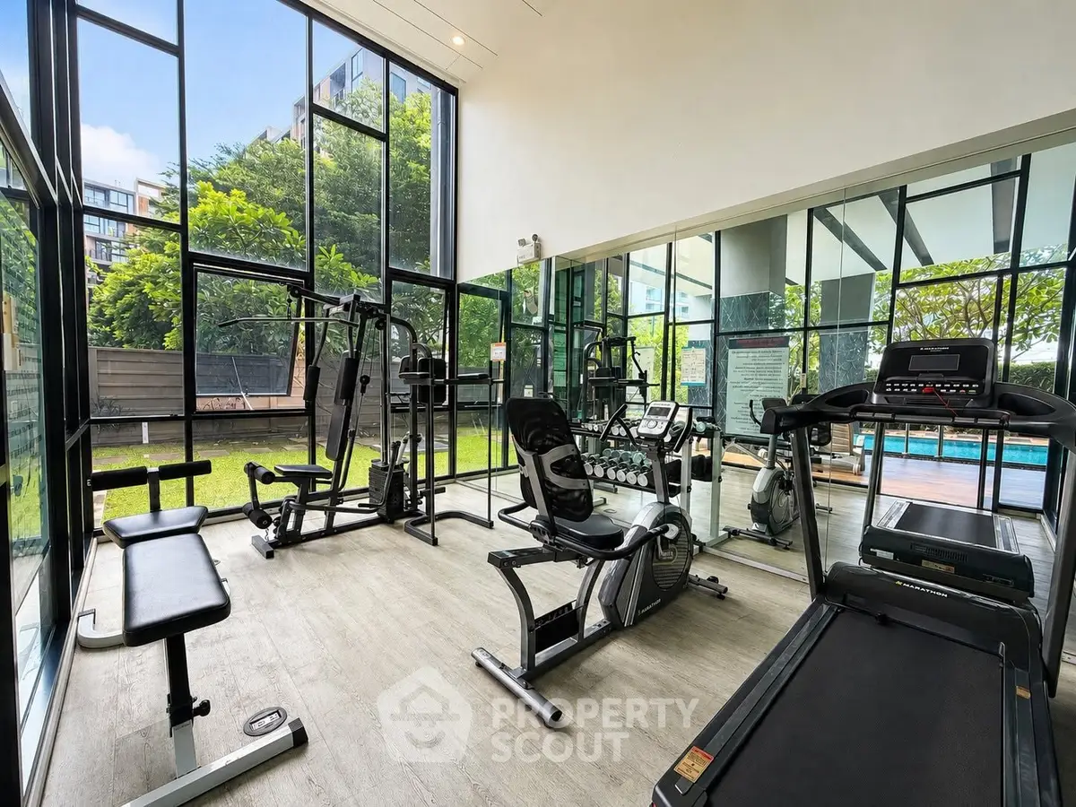 Modern gym with state-of-the-art equipment and large windows overlooking lush greenery.