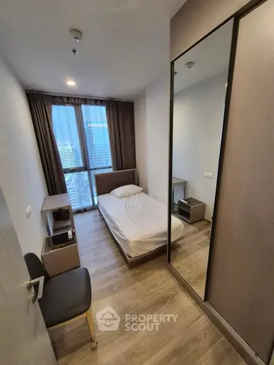 Modern compact bedroom with city view and sleek wooden flooring.