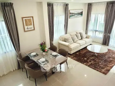 Elegant living room with modern decor, plush sofa, and dining area in a bright, airy space.