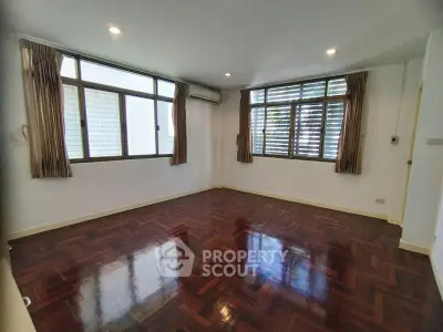 Spacious empty room with polished wooden floors and large windows
