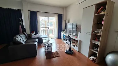 Cozy living room with modern decor and balcony view, featuring a comfortable sofa and entertainment center.