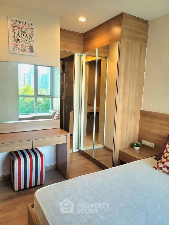 Modern bedroom with mirrored closet and city view, featuring stylish decor and natural light.