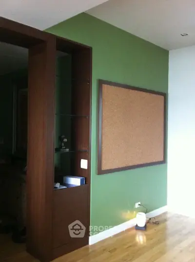 Modern interior with green accent wall and corkboard, featuring wooden shelving and sleek design.