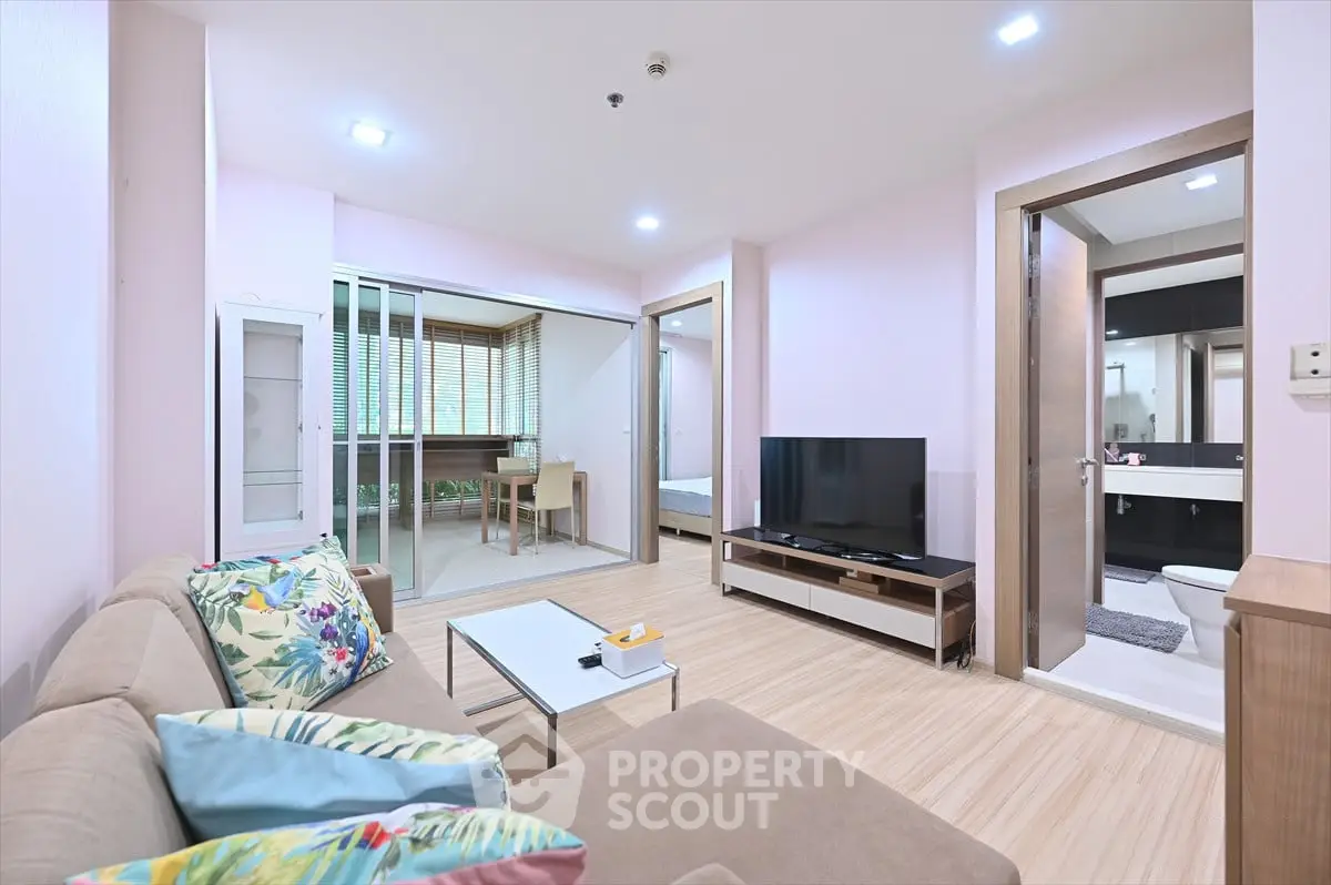 Modern living room with cozy sofa and TV, open layout to dining area and bedroom.