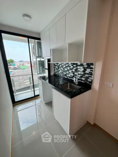Modern kitchen with sleek black countertops and stylish backsplash in a bright apartment
