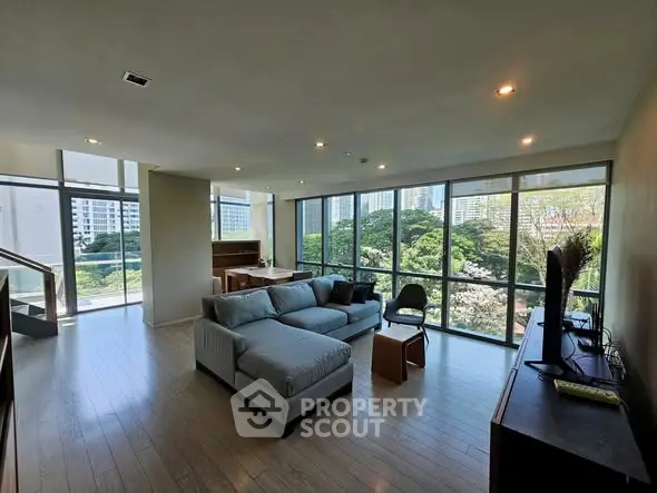 Spacious modern living room with large windows and city view, featuring stylish furniture and natural light.