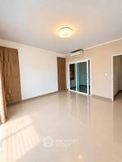 Spacious empty living room with glossy tiled floors and air conditioning.