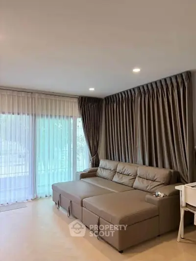 Spacious living room with elegant brown sofa and floor-to-ceiling windows for natural light.