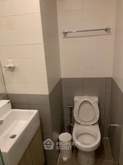 Modern bathroom with sleek design featuring a toilet and sink, ideal for compact spaces.