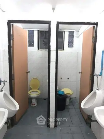 Public restroom with two stalls and urinals, featuring basic tile flooring and simple design.