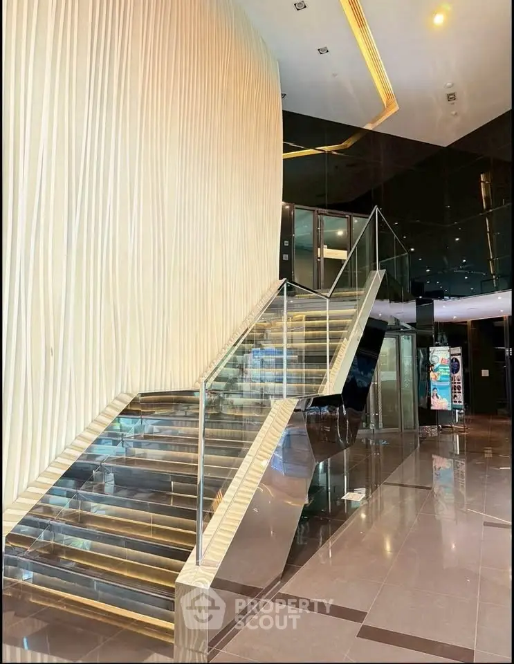 Luxurious modern building entrance with sleek glass staircase and elegant lighting