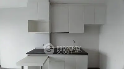 Modern minimalist kitchen with sleek white cabinetry and compact design.