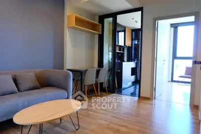 Modern living room with wooden flooring and open kitchen layout in a stylish apartment.