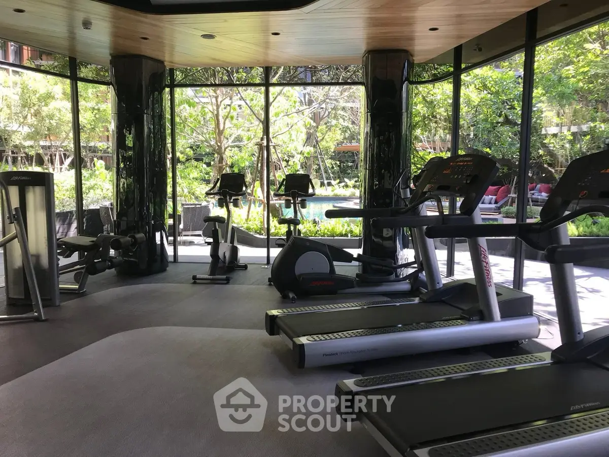 Luxurious gym with modern equipment and lush garden views in a high-end residential complex.