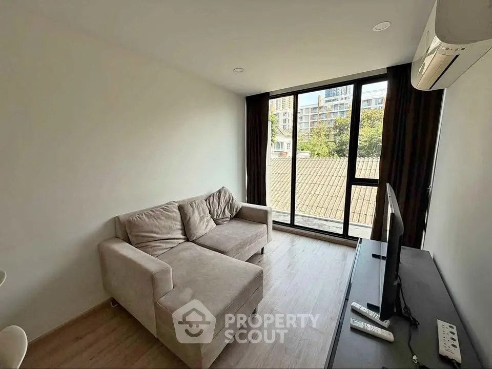 Modern living room with large window and cozy sofa in urban apartment