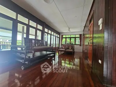 Spacious wooden interior with elegant seating and large windows in a serene setting.