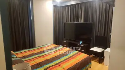 Cozy bedroom with colorful bedding and modern TV setup, perfect for relaxation.