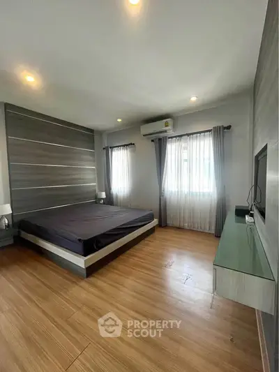 Spacious modern bedroom with wooden flooring and stylish decor
