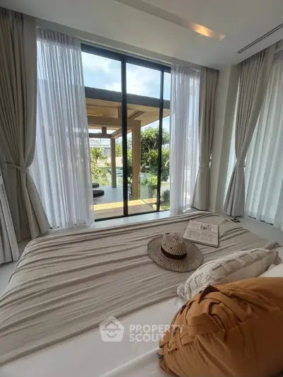 Luxurious bedroom with large windows opening to a stunning garden view, featuring elegant decor and natural light.