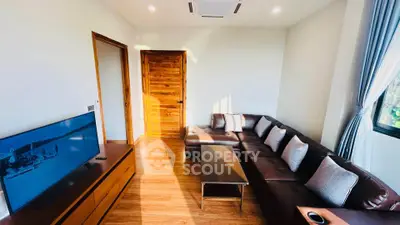 Spacious living room with modern leather sofa and large flat-screen TV, perfect for relaxation.
