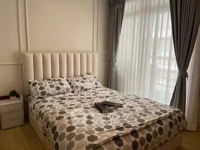Cozy bedroom with stylish decor and natural light through large windows, perfect for relaxation.