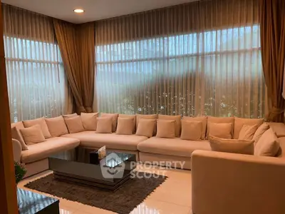 Spacious living room with elegant beige sectional sofa and floor-to-ceiling windows.