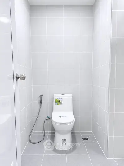 Modern minimalist bathroom with sleek white tiles and contemporary toilet design.