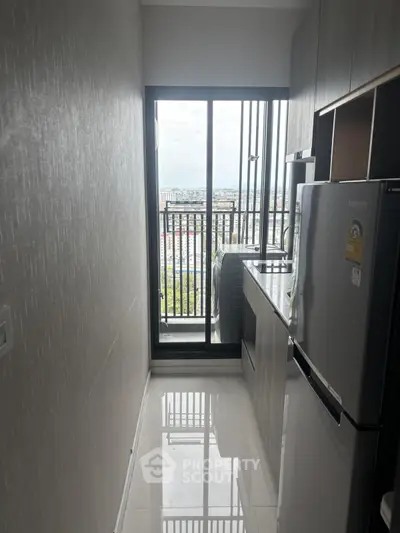 Modern kitchen with sleek appliances and stunning city view from high-rise balcony.