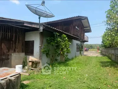Charming rustic house with lush green surroundings and satellite dish, perfect for countryside living.