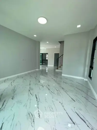 Spacious modern living room with elegant marble flooring and ample natural light.
