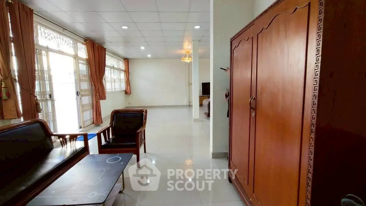 Spacious living room with elegant wooden furniture and large windows.