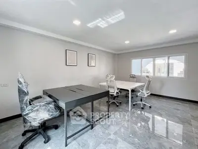 Modern office space with sleek desks and chairs, large windows, and polished floors.