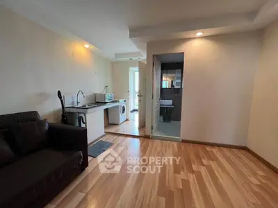 Modern apartment interior with open kitchen and living area, featuring hardwood floors and natural lighting.