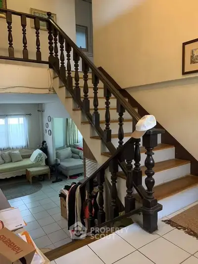 Charming staircase with wooden railing leading to cozy living area in a stylish home.