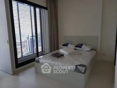 Modern bedroom with large window and city view, featuring a comfortable bed and sleek design.