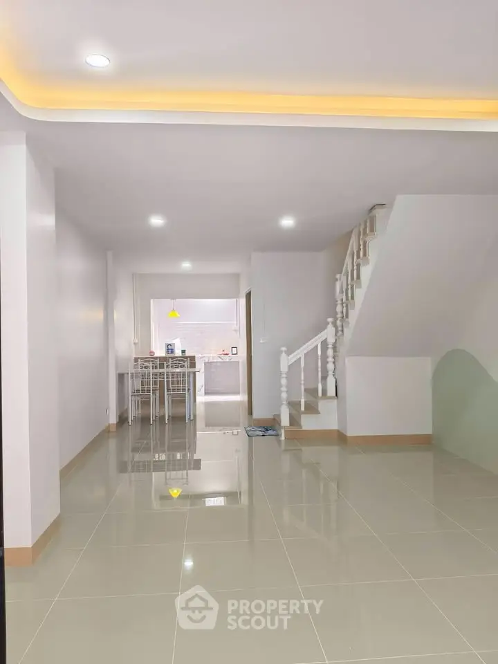 Spacious open-plan living area with modern staircase and sleek tiled flooring.