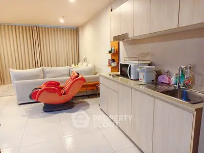 Modern living room with open kitchen and massage chair, perfect for relaxation and entertaining.