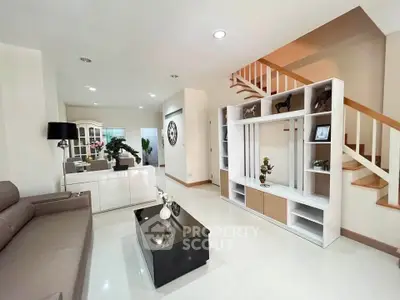 Spacious modern living room with elegant decor and open layout, featuring a stylish staircase and sleek furniture.
