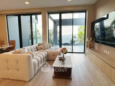 Luxurious living room with plush sofa and large windows opening to a spacious balcony.
