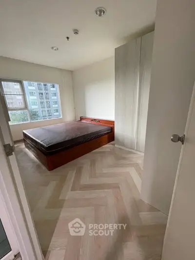 Spacious bedroom with large window and modern wooden flooring