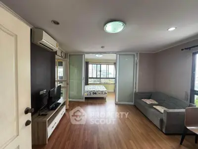 Spacious living room with wooden flooring and modern decor, featuring a cozy sofa and entertainment unit.