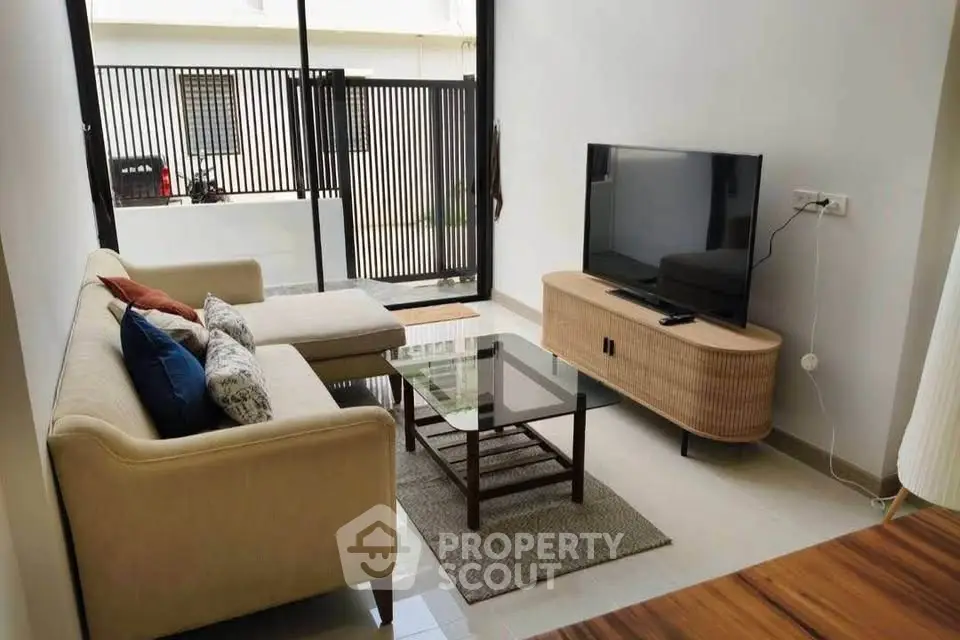 Modern living room with cozy sofa, sleek TV stand, and large window for natural light.