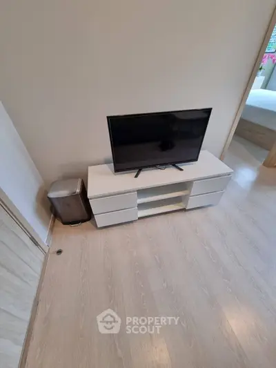 Modern living room with sleek TV stand and flat-screen TV, showcasing minimalist design and light wood flooring.