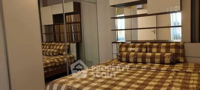 Cozy bedroom with checkered bedding and mirrored wardrobe in modern apartment.