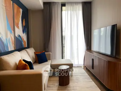 Modern living room with stylish decor and large TV, featuring a cozy sofa and abstract art.
