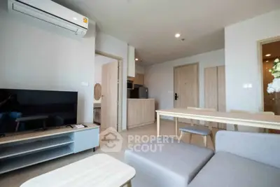 Modern living room with open kitchen, featuring sleek furniture and neutral tones for a cozy ambiance.