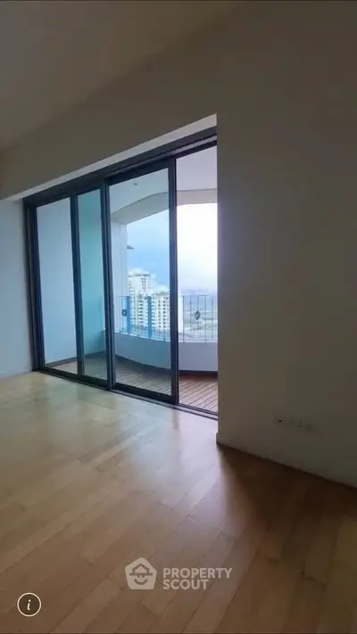 Spacious apartment with floor-to-ceiling windows leading to a balcony with city views.